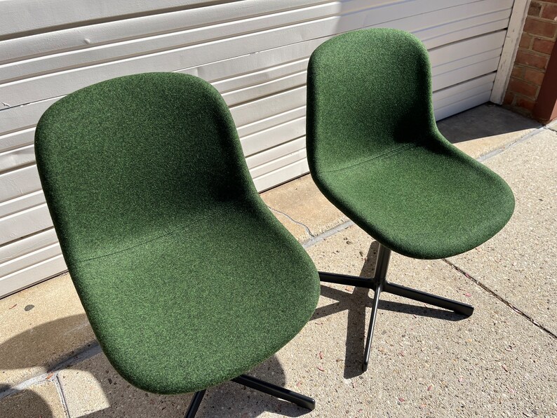 May include: Two dark green swivel chairs with black metal bases. The chairs are upholstered in a textured fabric.