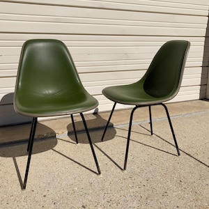 May include: Two green chairs with black metal legs. The chairs are made of molded plastic and have a simple, modern design.