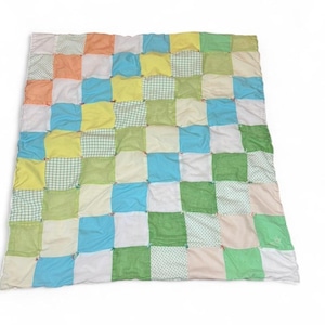 May include: A patchwork quilt featuring a grid pattern of colorful squares. The squares are in shades of white, orange, yellow, green, and blue. Some squares have patterns like gingham and polka dots. The quilt is a soft, handmade textile.