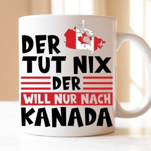 Könnte beinhalten: Weiße Keramiktasse mit einem schwarzen und roten Design. Die Tasse zeigt den Text "Der tut nix der will nur nach Kanada" und eine Umrandung Kanadas mit der kanadischen Flagge im Inneren.