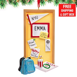 May include: A Christmas ornament shaped like a bulletin board with the name "EMMA" displayed. It features a NYU pennant, notes that say "EXAM TODAY!" and "PARTY THIS SATURDAY", and a pizza slice. A blue backpack and a drink with candy canes are also present.