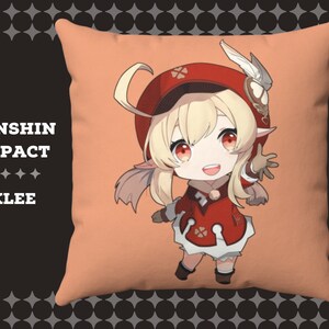 以下が含まれることがあります： 原神インパクトのビデオゲームのキャラクターが描かれたぬいぐるみ枕。キャラクターは、金髪の若い女の子で、赤と白の衣装を着て、赤い帽子をかぶっています。枕の背景は薄いオレンジ色です。