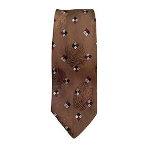 May include: A brown tie featuring a repeating pattern of seashells and diamond shapes. The seashells are in a darker brown, and the diamonds have red, black, and white accents. The tie is made of a smooth fabric.