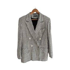 May include: A black and white houndstooth blazer with a double breasted closure and two front pockets.