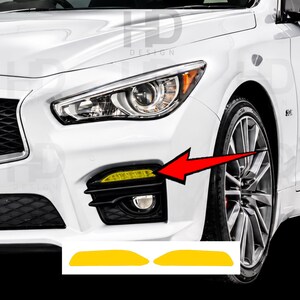 May include: A pair of yellow adhesive overlays designed for the fog light housing of a white vehicle. The overlays are shaped to fit the specific rectangular light section, shown installed on the car bumper with a red arrow pointing to them.