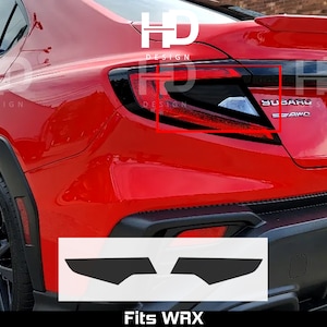 May include: A red Subaru WRX with black taillights and a black rear bumper. The car has a black rear diffuser and a black spoiler. The car is sitting on a black surface. The image shows a pair of black vinyl overlays for the taillights. The overlays are shaped like a wing and have a cutout for the taillight. The overlays are designed to fit the Subaru WRX. The text "Fits WRX" is printed below the overlays.