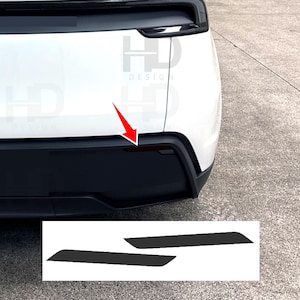 May include: A white vehicle's rear bumper with a black lower section and a red reflector. Two black rectangular decals are shown below the bumper, likely for customization or protection. The image includes the text "HD DESIGN".