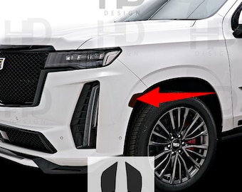 May include: A white Cadillac Escalade with black accents and a black wheel with a Cadillac logo. The car has a black front bumper with a black grille and black headlights. The car is parked on a white surface. The image also includes two black vinyl decals shaped like a pair of wings.