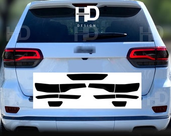 May include: A set of black vinyl tail light covers for a white SUV. The covers are designed to fit over the taillights and give them a blacked-out look.