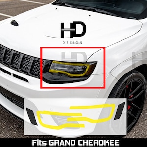 May include: A white Jeep Grand Cherokee front end featuring a black grille and a headlight assembly highlighted with a yellow outline. The image includes the text HD DESIGN and FITS GRAND CHEROKEE, with additional yellow line drawings of headlight shapes.