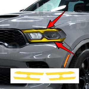 May include: A gray vehicle front end featuring a yellow headlight tint overlay applied to the passenger side light assembly. Two red arrows point to the yellow film. Below, two separate yellow adhesive decal pieces are displayed on a white background.