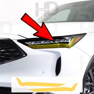 May include: A white car with yellow headlights and a set of two yellow vinyl decals. The decals are shaped like a curved line with a sharp point at the end.