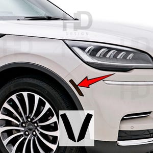 May include: A white car with black trim and a black wheel. The car has a black accent strip on the side of the front fender. The accent strip is shaped like a V.