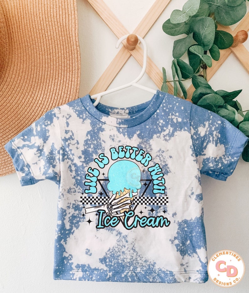 May include: A blue tie-dye t-shirt with a graphic of a skeleton hand holding a melting ice cream cone. The graphic has the text "Life is better with Ice Cream" in a retro font.