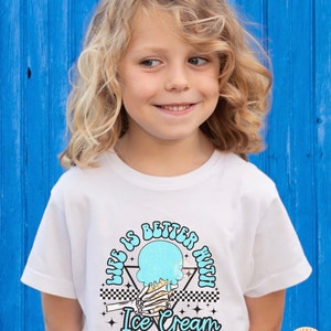 May include: A white t-shirt with a graphic design of a skeleton hand holding a melting ice cream cone. The text "Life is better with Ice Cream" is printed in a retro font around the ice cream cone.
