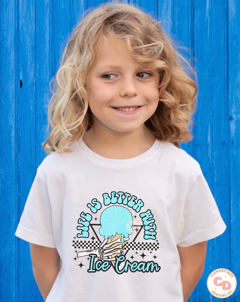 May include: A white t-shirt with a graphic design of a skeleton hand holding a melting ice cream cone. The text "Life is better with Ice Cream" is printed in a retro font around the ice cream cone.
