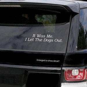 May include: A black car with a white vinyl sticker on the back window that reads "It Was Me. I Let The Dogs Out."
