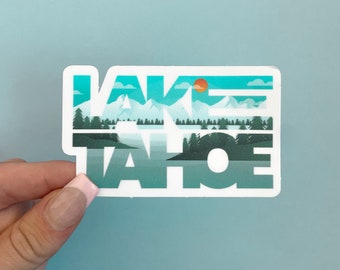 May include: A white sticker with the words "LAKE TAHOE" in blue and green letters. The letters are filled with a landscape scene of mountains, trees, and a lake.