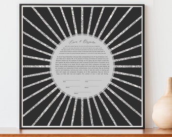 May include: A black and white framed print of a Jewish wedding ketubah with a silver glitter design. The ketubah features a circle with a Hebrew text inside and a sunburst design radiating outwards.
