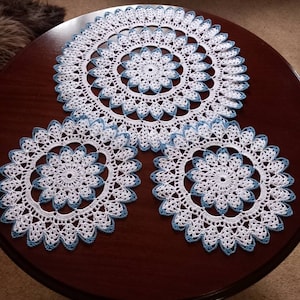 Set of 3 doilies, white and blue. Large doily measures 13.5ins (34cms) small doily measures 8.5ins (21.5cms).
