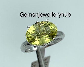 May include: A silver ring with a large, oval-shaped, light green gemstone. The gemstone is set in a prong setting.