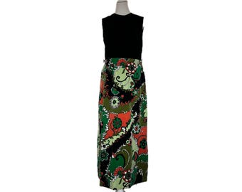 May include: A vintage sleeveless dress with a black bodice and a long skirt. The skirt features a colorful paisley pattern in shades of green, orange, and black. The dress is displayed on a white mannequin.