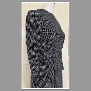 May include: A black and white geometric patterned dress with a long sleeve and a fitted bodice.