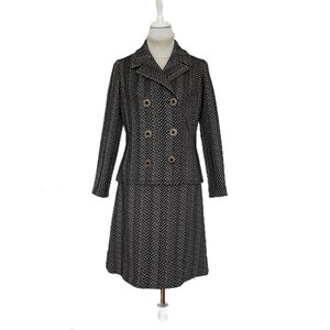 Könnte beinhalten: Ein zweiteiliger Vintage-Anzug in einem schwarz-weißen Fischgrätenmuster. Die Jacke hat ein doppelreihiges Design mit goldfarbenen Knöpfen. Der Rock ist ein klassischer A-Linien-Stil. Der Anzug wird auf einer Schaufensterpuppe präsentiert.
