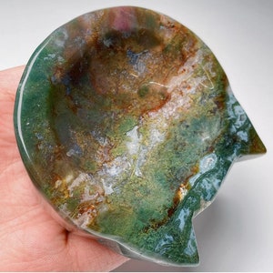 May include: A green, brown and white agate cat dish. The dish is carved from a single piece of agate and has a natural, organic shape.