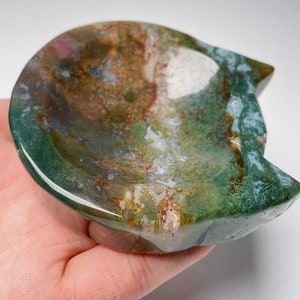 May include: A green, brown and white agate stone carved into a cat-shaped dish. The dish is shallow and has a smooth, polished surface.