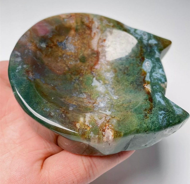 May include: A green, brown and white agate stone carved into a cat-shaped dish. The dish is shallow and has a smooth, polished surface.