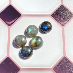 May include: Five round, iridescent labradorite gemstones in shades of gray, blue, and green. The stones are smooth and polished, with a slight sheen.