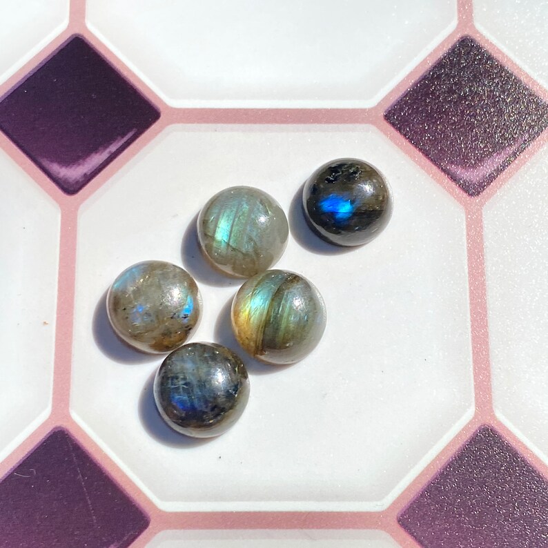 May include: Five round, iridescent labradorite gemstones in shades of gray, blue, and green. The stones are smooth and polished, with a slight sheen.