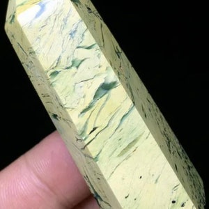 Könnte beinhalten: Eine grüne und gelbe Kristallspitze mit einer glatten, polierten Oberfläche. Der Kristall hat ein einzigartiges Marmormuster und ist pyramidenförmig.