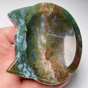 May include: A green, brown, and white agate stone carved into a cat-shaped dish. The dish has a smooth, polished surface and a shallow bowl.