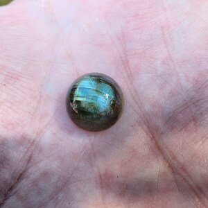 May include: A round, green and gold labradorite gemstone cabochon.