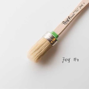 May include: A close-up of a small, round paint brush with natural bristles. The brush is attached to a wooden handle with a green and silver ferrule. The handle is labeled "Paint Pixie Joy #1" and "Made in Italy".