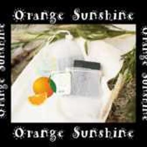 May include: A white cotton drawstring bag with the text "Orange Sunshine" printed on the sides. The bag contains a small bar of soap and a small bag of bath salts. There is also a whole orange and a sliced orange in the bag.