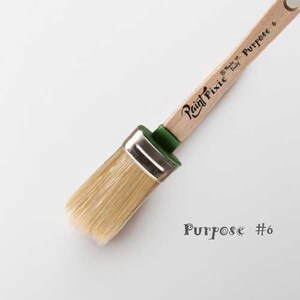 May include: A close-up of a Paint Pixie Purpose #6 paintbrush with a wooden handle and a green ferrule. The brush is made in Italy.