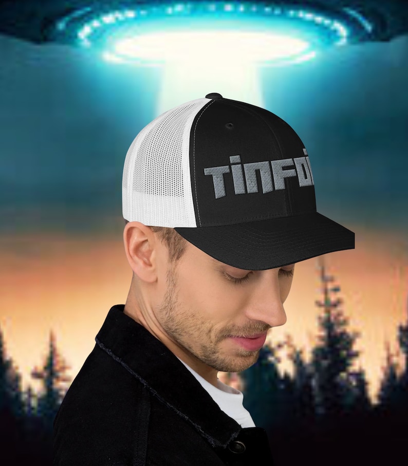 May include: A black and white trucker hat with a grey embroidered logo that says "Tin Foil".