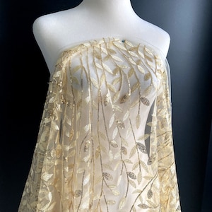 May include: Gold leaf and sequin embroidered fabric with a delicate leaf pattern. The fabric is sheer and has a soft, flowing texture.