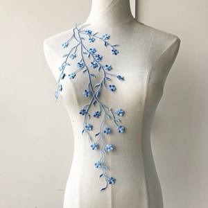 Peut inclure: Applique de broderie florale bleu clair avec des branches délicates et de petites fleurs. Ce motif est parfait pour ajouter une touche d'élégance aux vêtements, aux accessoires ou aux projets de décoration intérieure.