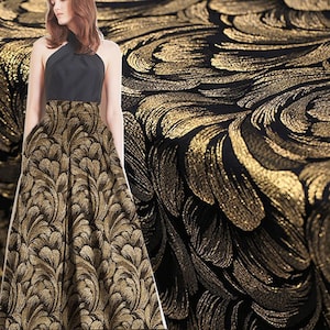 Puede incluir: Tela negra con un patrón de brocado dorado. El patrón presenta un diseño floral en espiral.