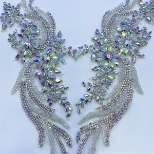 Può includere: Un paio di decorazioni in cristallo iridescente a forma di fiore. Le decorazioni sono realizzate in cristalli trasparenti con un effetto arcobaleno. Sono perfette per aggiungere un tocco di brillantezza a qualsiasi progetto.