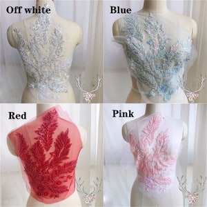 May include: Four different colored beaded lace appliques on a white mesh fabric background. The appliques are in the shapes of leaves and flowers. The colors are off-white, blue, red, and pink.