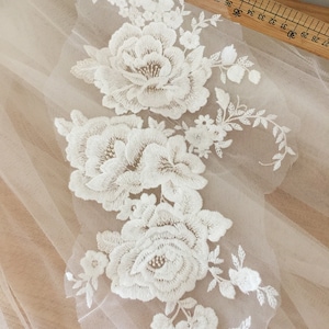 May include: White floral lace applique with delicate embroidery details. The lace features a cluster of three large roses and smaller floral accents.