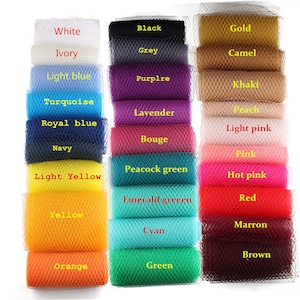 May include: A display of tulle fabric rolls in a range of colours, from white and black to gold and pink. Each roll is labelled with its colour name, including "Navy," "Orange," and "Green." The tulle is arranged in neat rows, showcasing a wide spectrum of hues.