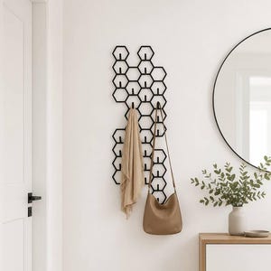 Peut inclure: Un porte-manteau mural en métal noir composé d'un motif géométrique en nid d'abeille avec plusieurs cadres hexagonaux. Le support maintient une écharpe en tissu beige et un sac à bandoulière en cuir marron clair pour suspendre des objets.