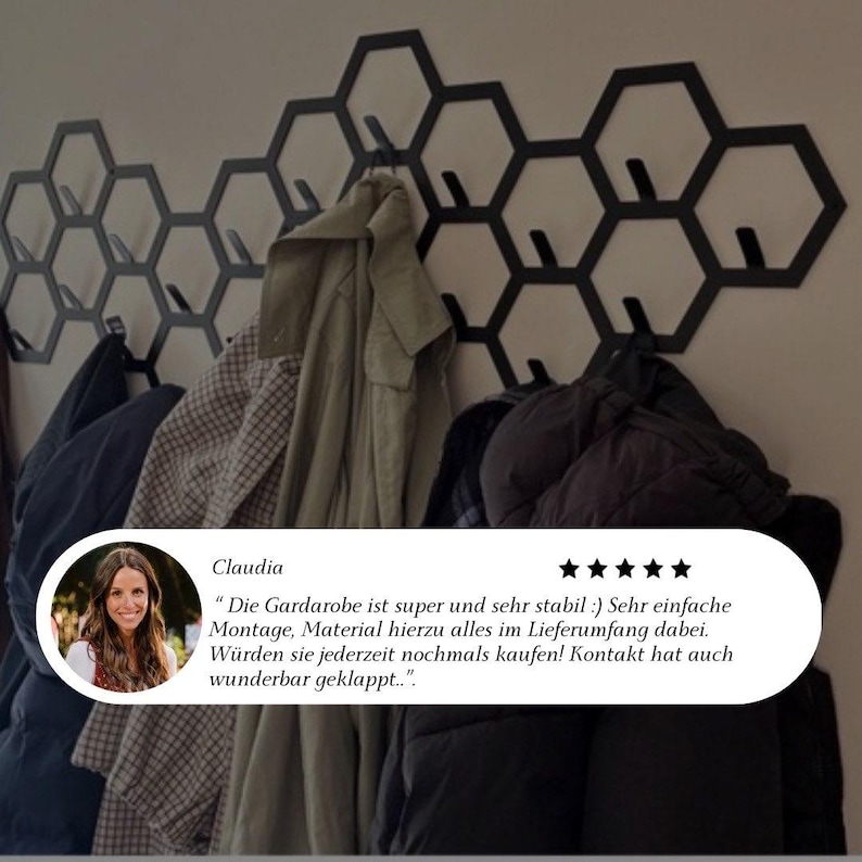 May include: Black metal honeycomb wall-mounted coat rack with multiple hooks. Various coats and jackets hang from the hooks. The wall is painted a light color. Text in German is visible in the image.