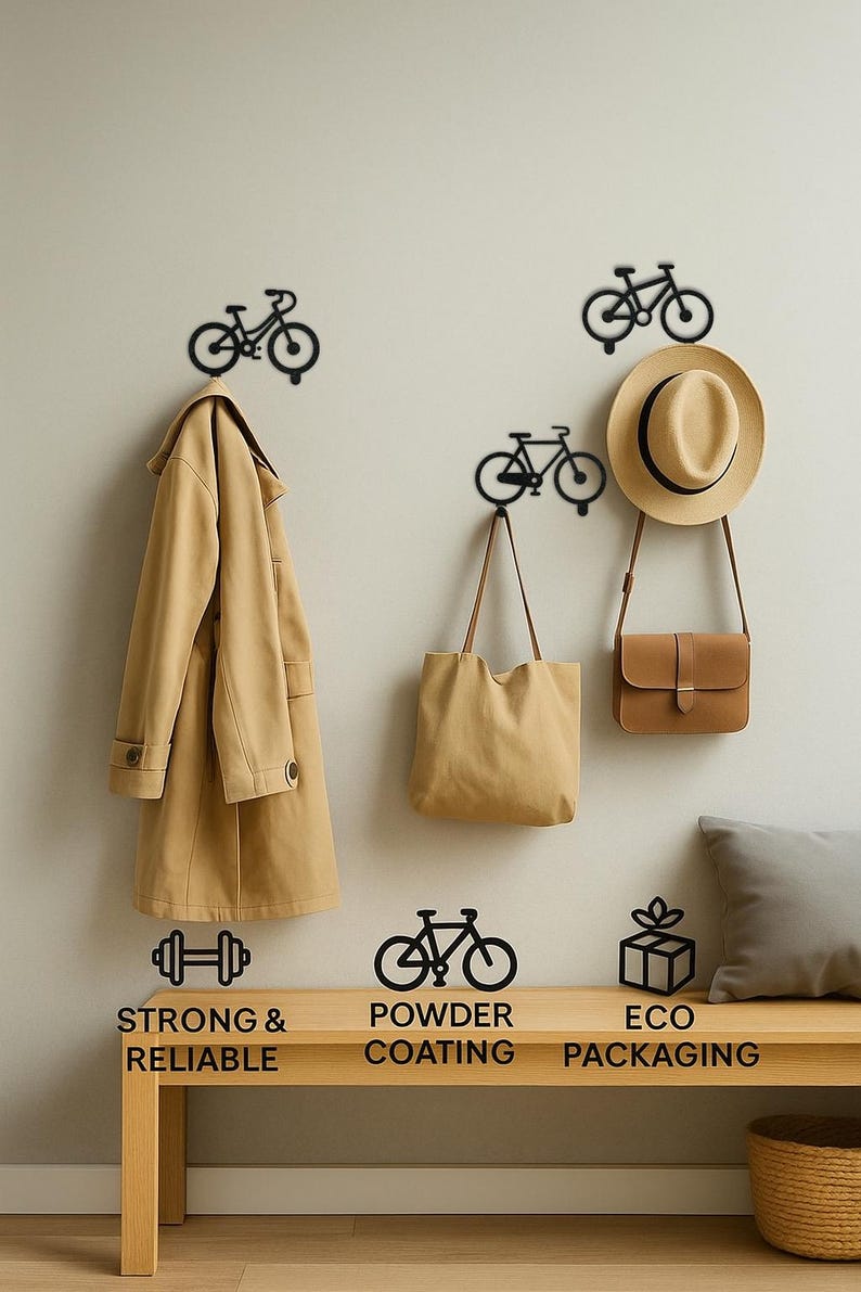 Op de afbeelding: Zwarte metalen fietsvormige wandhaken met een beige jas, een draagtas en een bruine hoed en tas. De haken zijn gemonteerd op een lichtgekleurde muur boven een houten bank. De tekst luidt "Strong & Reliable", "Powder Coating" en "Eco Packaging".